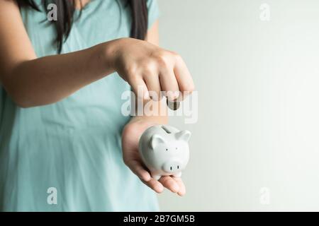 Sparen und Geschäftskonzept, süßes Mädchen mit Schweinebank und Münzen zu Hause Stockfoto