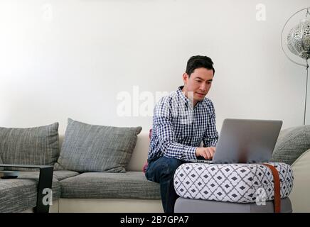 Mann, der von zu Hause aus mit einem Laptop im Wohnzimmer arbeitet Stockfoto