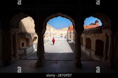 Frau im roten Kleid, die zu Fuß in der Hawa Mahal Palast mit Bogen Silhouette, Rajasthan, Indien Stockfoto