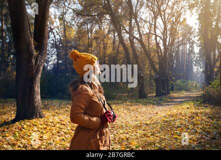 Frau in braune Jacke und gelben Hut eine Aufnahme mit alten Vintage Foto-Kamera im herbstlichen Wald Stockfoto