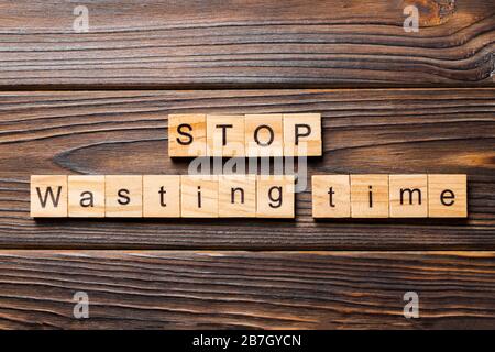 Verschwenden Sie keine Zeitwort mehr, das auf Holzklotz geschrieben wurde. Verschwenden Sie keine Zeit mehr mit Text auf Holztisch für Ihr Desing, Top-View-Konzept. Stockfoto