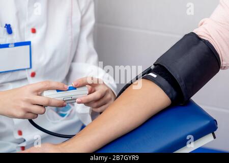 Der Arzt kontrolliert den Blutdruck der jungen Frau in der Nähe. Stockfoto