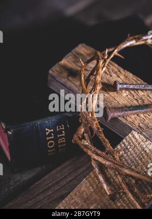 Nahaufnahme von Holzkreuz und Dornenkrone mit der heiligen bibel in einem dunklen rustikalen Ambiente Stockfoto