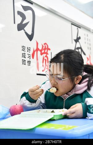 (200316) -- GUIYANG, 16. März 2020 (Xinhua) -- EIN Student isst Mittagessen im Klassenzimmer in der Nr. 1 Experimentelle Mittelschule in Guiyang, südwestchinesische Provinz Guizhou, 16. März 2020. Fast 1 Million Schüler in ihrem Abschlussjahr der Senior- und Juniorhochschulen in der südwestchinesischen Provinz Guizhou besuchten nach einem längeren Lunar-Neujahrsfest aufgrund des Ausbruchs des Coronavirus Schulen. Maßgeschneiderte Schulbusse, Masken, Temperaturkontrollen, spezielle Routen zu den Klassenzimmern, um das Sammeln von Menschenmassen zu verhindern - der erste Schultag zurück schien für die Schüler besonders und sicher. (Xi Stockfoto