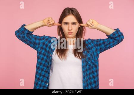 Hören Sie nicht zu! Portrait des unzufriedenen verärgerten Mädchens in karierten Hemdschließenden Ohren und mit ärgerlicher irritierter Ausdrucksweise aussehend, wobei Confli ignoriert wird Stockfoto