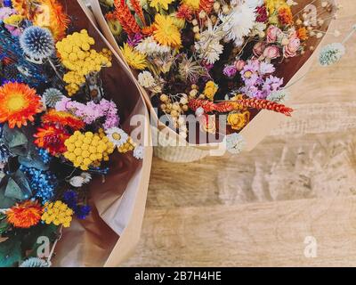 Leuchtend getrocknete Blumenarrangement in Rot, Gelb und Purpeln auf Holzhintergrund Stockfoto