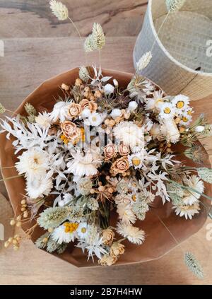 Getrocknete Blumenarrangement für eine Hochzeit in neutralen weichen Beige- und Weißtönen auf Holzhintergrund Stockfoto