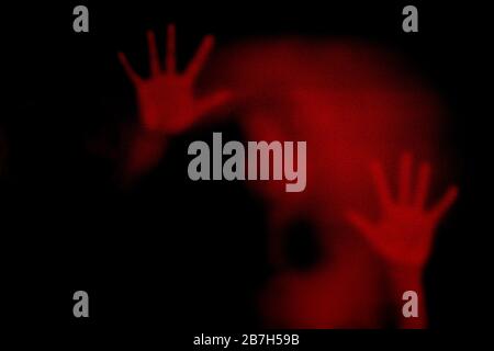 Roter Schatten der Frau auf dem Milchglas, der gefährlich, Angst, Hilfe, Spukhaft, Horror, Schreckgespenst, Lockdown, Infizierte, Virus und Plage darstellt. Stockfoto