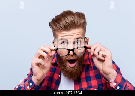 Nahaufnahme des schockierten staunenden Mannes im karierten Hemd, das seine Brille berührt Stockfoto
