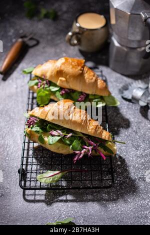 Französisches Croissant mit Gemüse. Frühstück mit köstlichem Kaffee. Gesundes Essen und Getränk. Brötchen mit Salat. Stockfoto