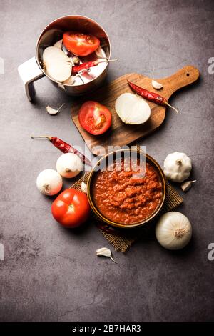 Zwiebeltomate Masala oder Püree für indische Soße, serviert in einer Schüssel mit rohem Tamatar, zahlt und Lehmun und roten Chili, selektiver Fokus Stockfoto