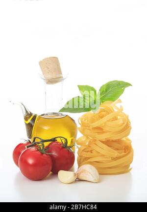 Pasta Rezeptkonzept. Unbehackte Tagliatelle Nester, Basilikum, Tomaten, Olivenöl und Knoblauch isoliert auf weißem Hintergrund. Traditionelle italienische Lebensmittelpräpara Stockfoto