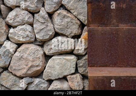 Nahaufnahme eines rostigen Schrittes einer Treppe neben einer Steinmauer Stockfoto