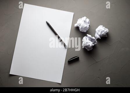 Leeres Whitepaper, Schreibstift und drei zerknitterte Blätter auf Betongrund Stockfoto