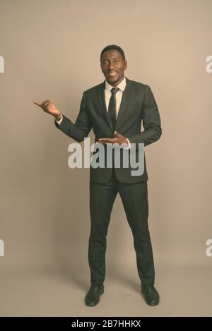 Studio-Schuss des jungen gutaussehenden afrikanischen Kaufmanns vor grauem Hintergrund Stockfoto