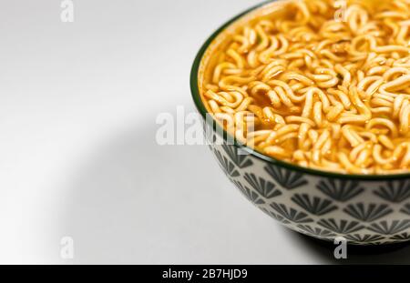 Schüssel mit Nudeln, Nudelsuppe in einer Tasse, asiatische Mahlzeit isoliert auf weißem Hintergrund Draufsicht Schüssel von rechts Stockfoto