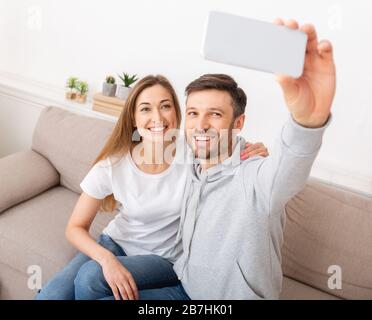 Glückliches junges Paar, das selfie vom Umzug in eine neue Wohnung nimmt Stockfoto