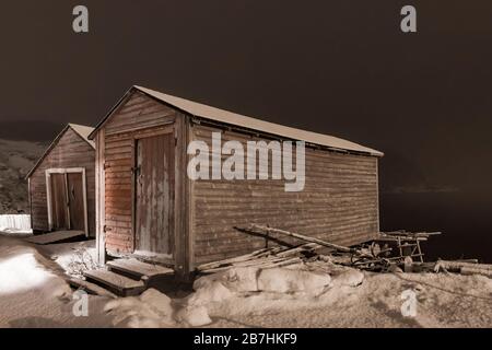 Stages, in denen Fischgeräte untergebracht und Köder und Fische verarbeitet wurden, nachts im alten Fischerdorf Dunfield in Neufundland, Kanada Stockfoto