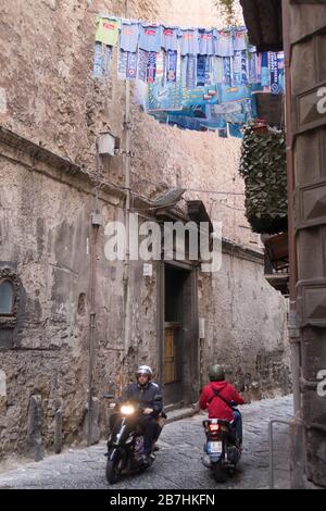 Uniformen und Schals des FC Neapel werden vor einem Fenster in der Innenstadt von Neapel gehängt Stockfoto