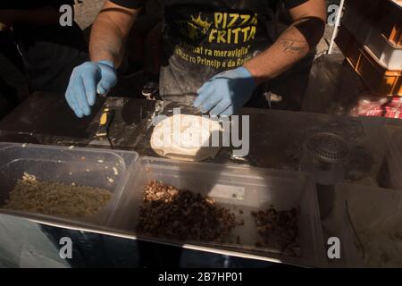 Ein Pizzakoch, der Teig mit Käse und Fleisch zur Zubereitung von Pizza aus dem Bratpfanne betäubt Stockfoto