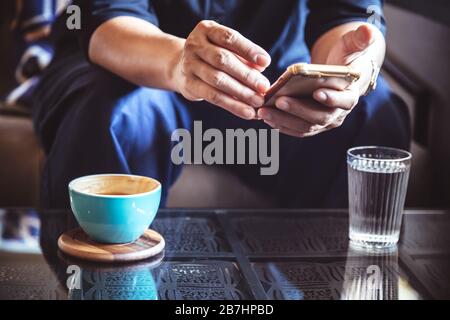 Geschäftsmann mit Smartphone Investment News und Antwort-E-Mail treffen im Café zu Lesen bestätigen. Mann trinken latte Kaffee vor der Arbeit Stockfoto