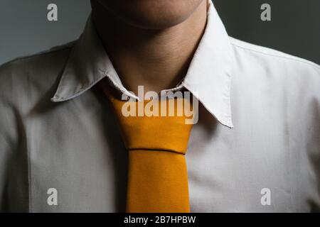 Ein junger Mann in weißem Anzug und orangefarbener Krawatte Stockfoto