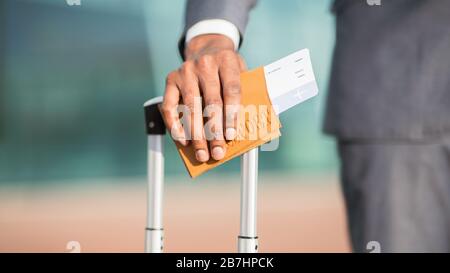 Businessman Holding Boarding Pass Mit Koffer Am Flughafen, Closeup Stockfoto