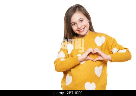 Studio-Porträt eines kleinen Mädchens auf weißem Hintergrund, das mit ihren Händen eine Herzgeste macht. Förderung eines Kindes, humanitäre Hilfe, Zusammenarbeit und Spenden Stockfoto