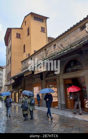 FLORENZ ITALIEN REGNET ÜBER DIE BRÜCKE PONTE VECCHIO UND GOLDSMITH- ODER SILBERSCHMIEDEGESCHÄFTE UND EINEN ROTEN REGENSCHIRM Stockfoto