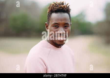 Glücklicher Afrikaner steht und lächelt. Nahaufnahme. Hochformat. Stockfoto