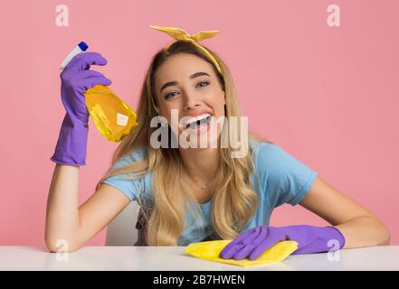 Hausfrau hält Spray in der Hand und wischt Lappen des Tisches Stockfoto