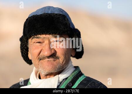 Porträt eines freundlichen usbekischen Hirten in traditioneller Kleidung und einem Fellhut, Ayaz Kala, Kyzylkum-Wüste, Karakalpakstan, Usbekistan Stockfoto