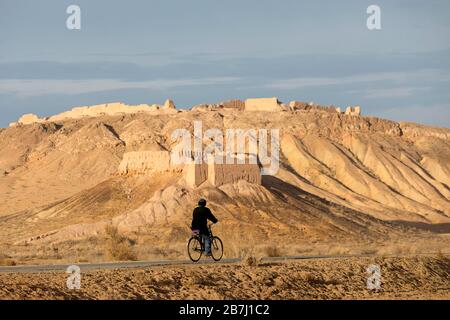 Senior Shepherdh mit dem Fahrrad auf den Ruinen der antiken Festung Ayaz-Kala auf einem Hügel in der Wüste Kyzylkum, Usbekistan Stockfoto