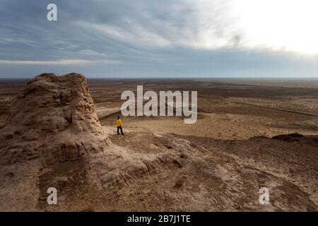 Frau, die sich auf den Ruinen der archäologischen Stätte Ayaz-Kala auf einem Hügel mit Blick auf die Wüste Kyzylkum, Karakalpakstan, Usbekistan, befindet Stockfoto