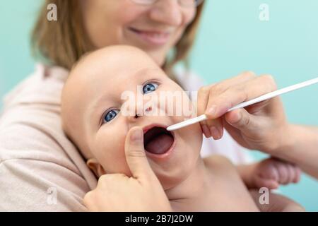 Arzt Kinderarzt untersucht Kehle und Zahn. Mutter hält Baby mit den Händen, während sie die Gesundheit eincheckt. Medizin, Gesundheitswesen, Pediatrie und Menschen Stockfoto