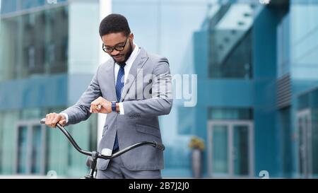 Gut aussehender schwarzer Manager, der die Zeit auf der Armbanduhr überprüft Stockfoto