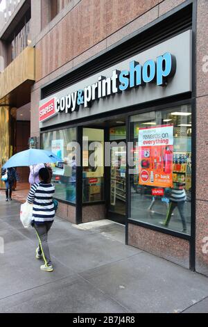 NEW YORK, USA - 10. JUNI 2013: Menschen gehen am Staples Copy and Print Shop in New York vorbei. Staples Inc. Wurde 1986 gegründet und verfügt über 2.000 Geschäfte in 26 Filialen Stockfoto