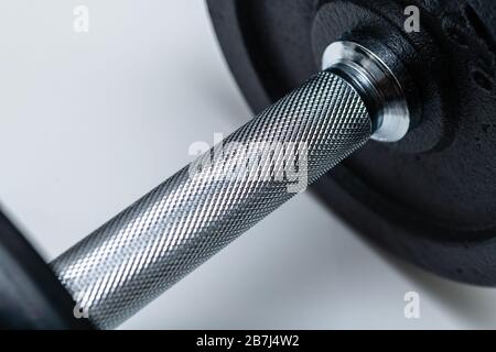 Nahaufnahme des verstellbaren Hantelgriffs mit aufgesetzten Gewichten auf weißem Hintergrund. Konzept von Training, Fitness und Bewegung für ein gesundes Leben. Stockfoto