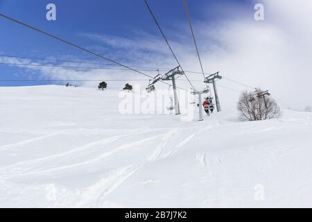 Zwei- und viersitzige Seilbahnen im Skigebiet Dombai mitten in der Wintersaison. Kreuzung zweier Straßen Stockfoto