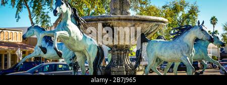 Ein Panoramaformat der geliebten arabischen Pferdestatuen aus Bronze mit Wasserbrunnen, entlang des Bereichs "Artwork the Line" der Altstadt von Scottsdale, AZ, USA Stockfoto
