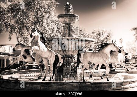 Die geliebte arabische Pferdestatue aus Bronze mit Wasserbrunnen, entlang des "Kunstwerks der Linie"-Bereichs der Altstadt von Scottsdale, AZ, in dramatischem Sepia-Ton Stockfoto