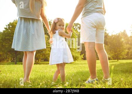 Fröhliche Familienspaziergänge auf dem Gras im Sommerpark. Kinderschutztag. Stockfoto