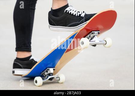 Nahaufnahme der Füße eines Teenagers auf einem Skateboard, das bereit ist, eine Fahrt über die Halfpipe zu beginnen. Stockfoto