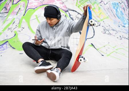 Junger lateinischer Skater-Mann posiert mit Skateboard im Skatepark. Stockfoto