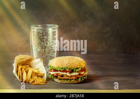 Süßes Getränk mit Kohlensäure in einem Glas- und Hamburger, salzige Snacks, Brezeln, Pommes. Stockfoto