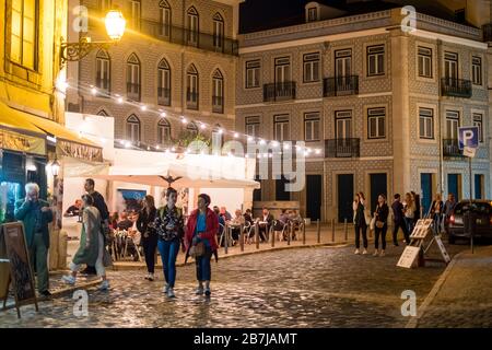 Touristen schlendern nachts durch Kopfsteinpflaster im Stadtteil Alfama, Lissabon, Portugal Stockfoto