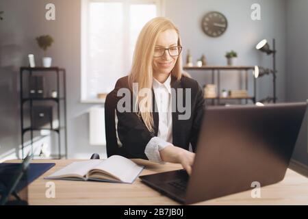 Eine reife Dame im Business-Anzug, die im Büro am Laptop arbeitet Stockfoto