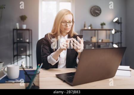 Portrait der Frau in Brillen mit Smartphone im Büro Stockfoto