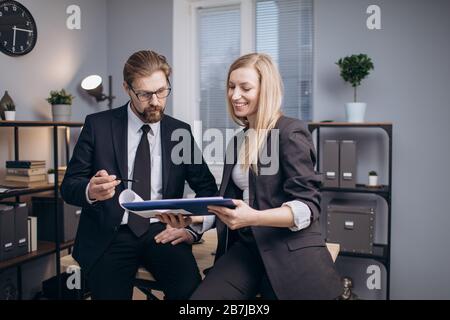 Geschäftspartner, die im Büro stehen und Dokumente lesen Stockfoto
