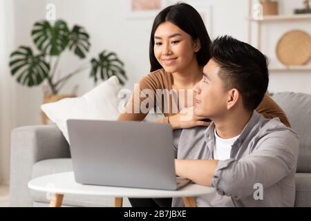 Junge philippinische Paare verwenden zu Hause einen Laptop Stockfoto